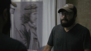 Ni-Naadamaadiz_ Red Power Rising - Tyler Cameron looking in a mirror with a photo of his father, Louis Cameron. Courtesy of Makwa Creative 